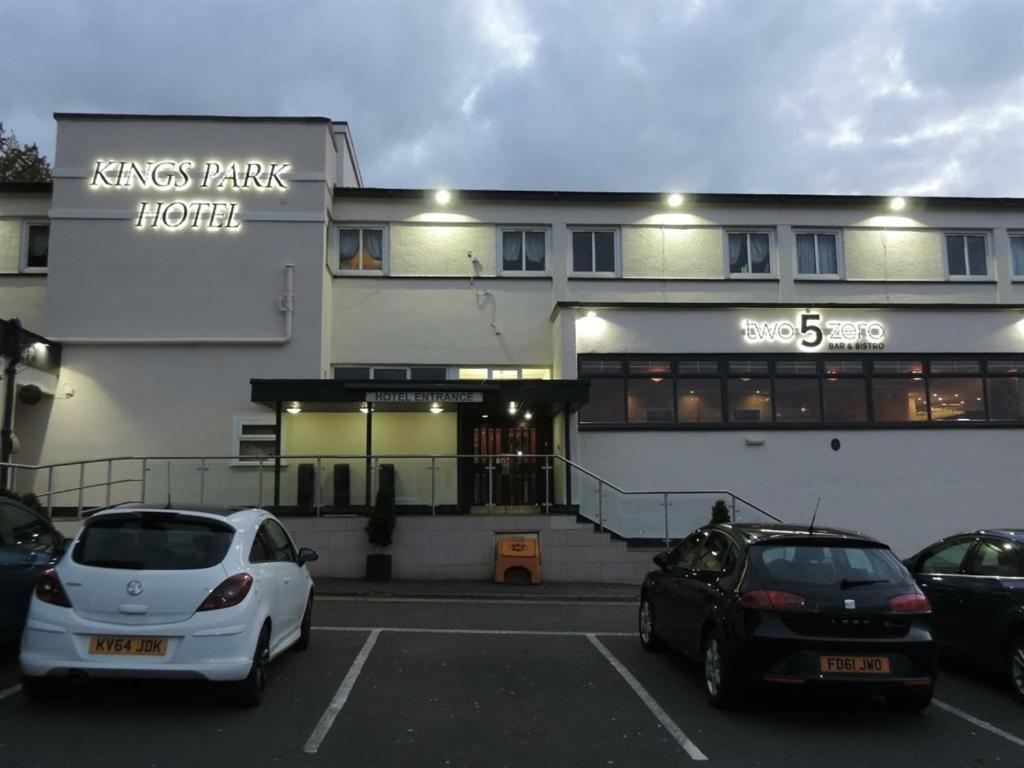 zwei Autos auf einem Parkplatz vor einem Gebäude geparkt in der Unterkunft Kings Park Hotel in Glasgow