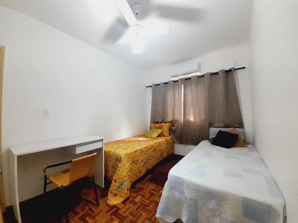 um pequeno quarto com 2 camas, uma secretária e uma mesa em APTO - 1,3 km da AFONSO PENA - 3 quartos com ar condicionado em Campo Grande