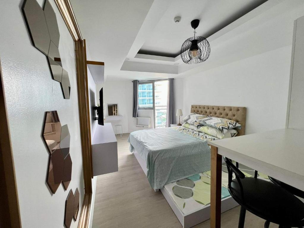 a bedroom with a bed and a table and a desk at Azure North San Fernando Pampanga in San Fernando