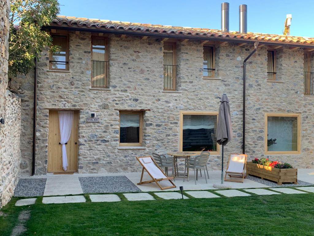 Cette maison en pierre dispose d'une terrasse, d'une table et de chaises. dans l'établissement CAL GALL rural Cerdanya, à Bellver de Cerdanya