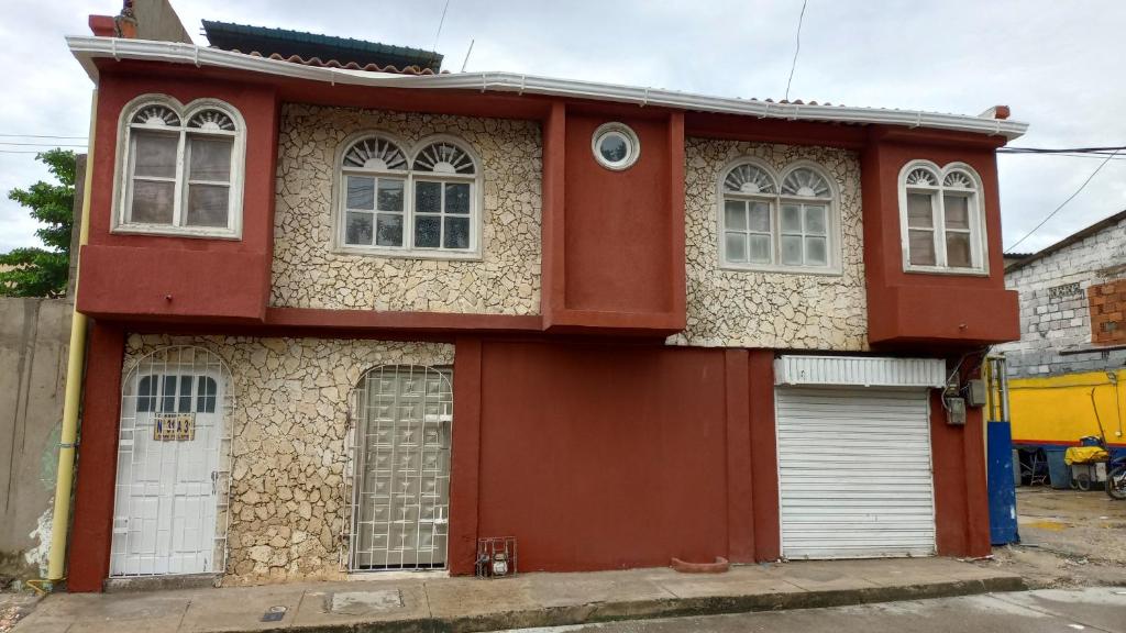 Maison rouge avec portes et fenêtres blanches dans l'établissement Alojamiento San Felipe, à Carthagène des Indes