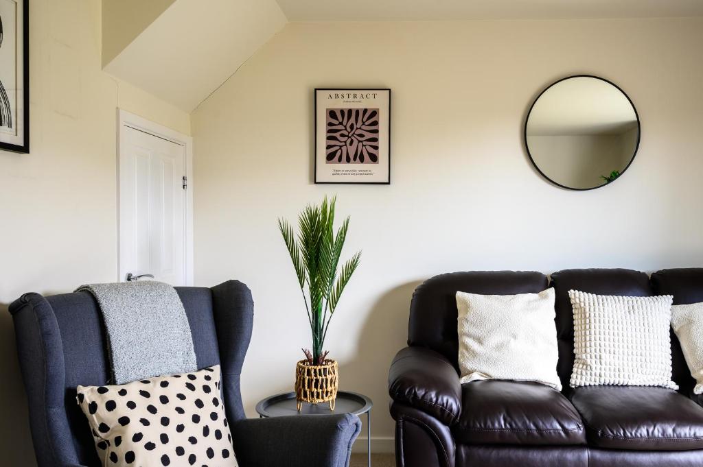 a living room with a leather couch and a mirror at Wykebeck Mount by Our Home Short Stays in Killingbeck