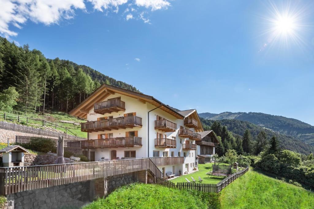 a building on a hill with the sun in the sky at Planatschhof in Villnoss