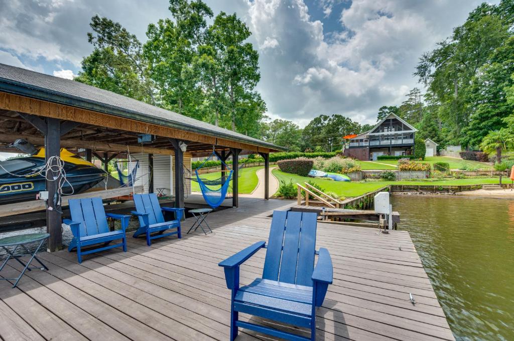 a wooden deck with blue chairs and a boat at Luxe Lake Sinclair Living Private Dock and Beach! in Resseaus Crossroads
