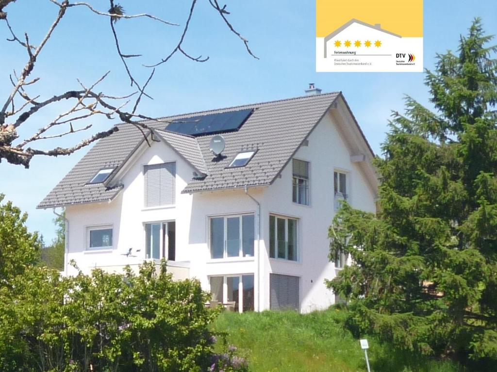 a house with a solar roof on top of a hill at Ferienwohnung Schwarzwald-Alpenblick in Lenzkirch