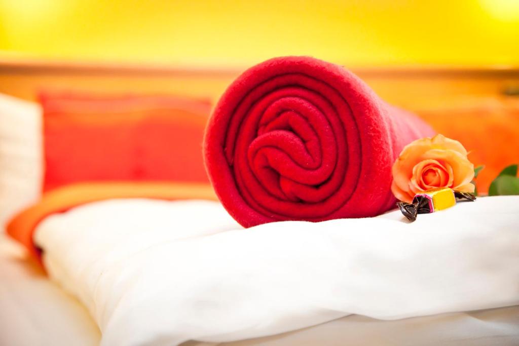 a red pillow with two roses on top of a bed at Hotel bei Liebe's in Erlenbach am Main