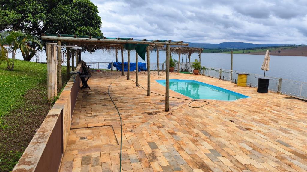 a swimming pool on a deck next to a body of water at Canto do lago pousada in Guapé