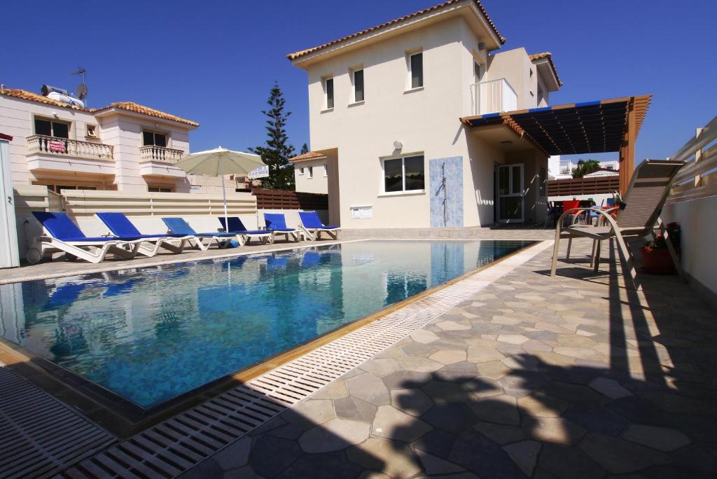 a swimming pool in front of a house at Maouris Villa in Protaras
