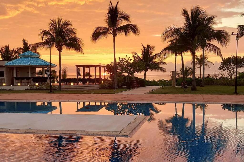 uma piscina com palmeiras e um gazebo em MAREAZUL Beachfront Apartment 2BR Private Pool Casa Áncora em Playa del Carmen