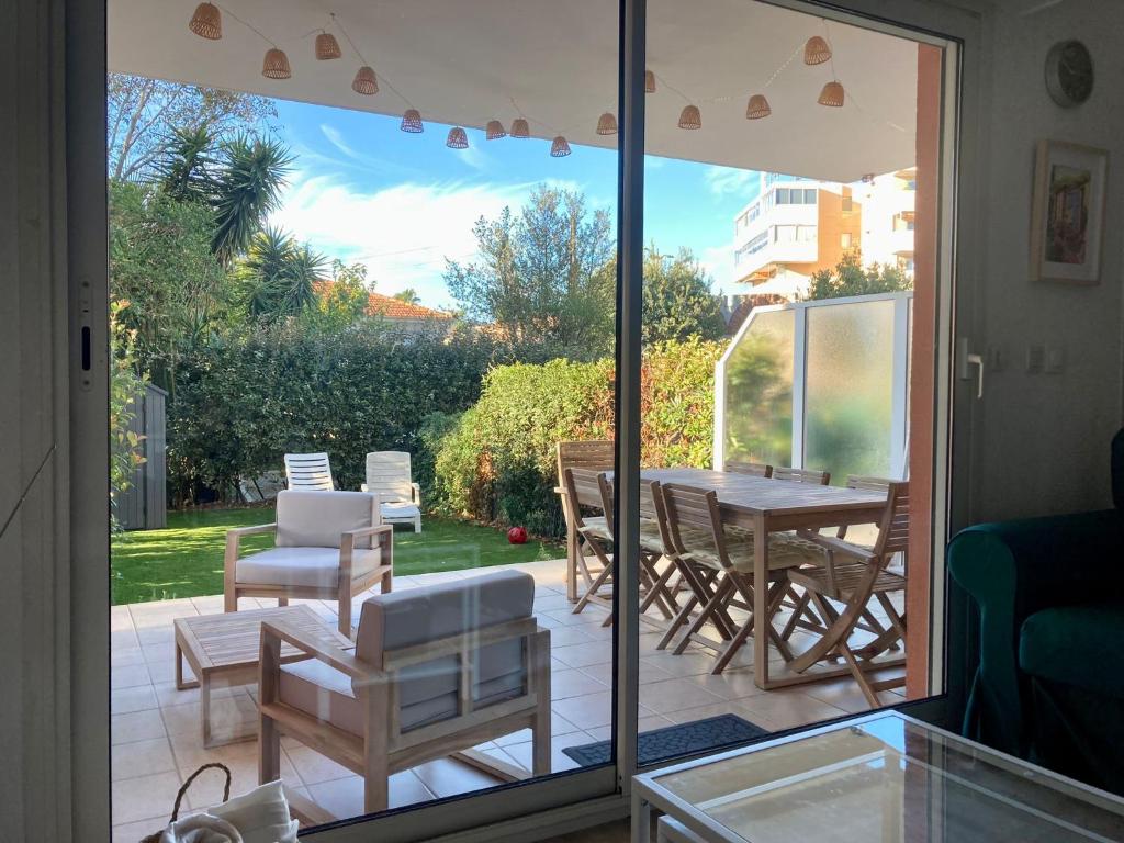 d'une terrasse avec une table, des chaises et une porte coulissante en verre. dans l'établissement Appartement F4 en résidence Rez de Jardin, à Fréjus