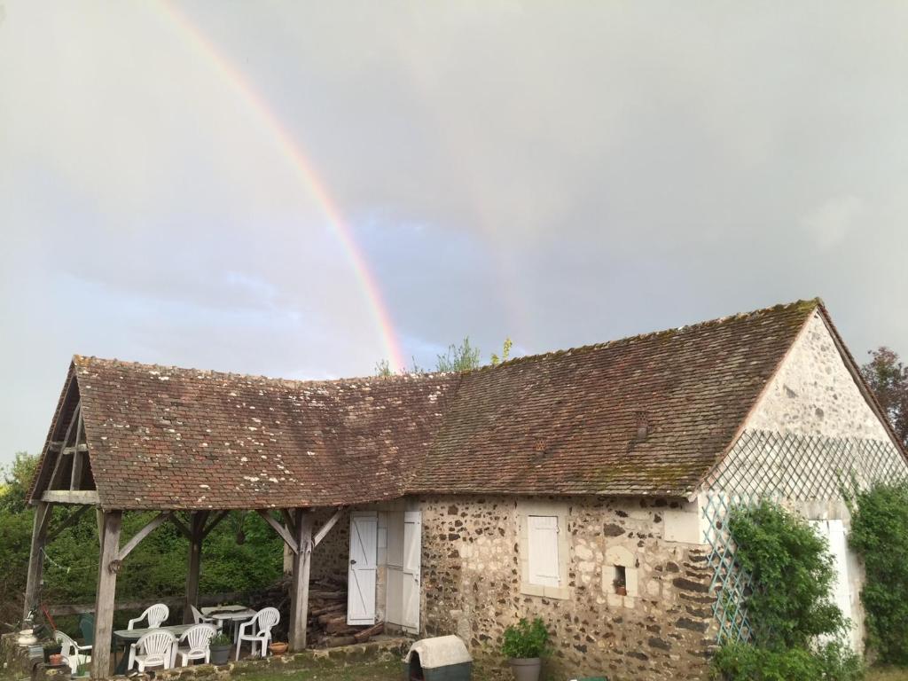CoulongéPetit Moulin Renaissance的石屋上方的彩虹,配有桌椅