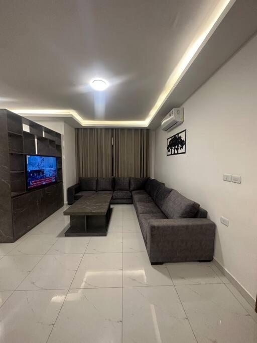 salon z kanapą i telewizorem w obiekcie cozy home near all services (19) w mieście Rujm ash Sharāʼirah