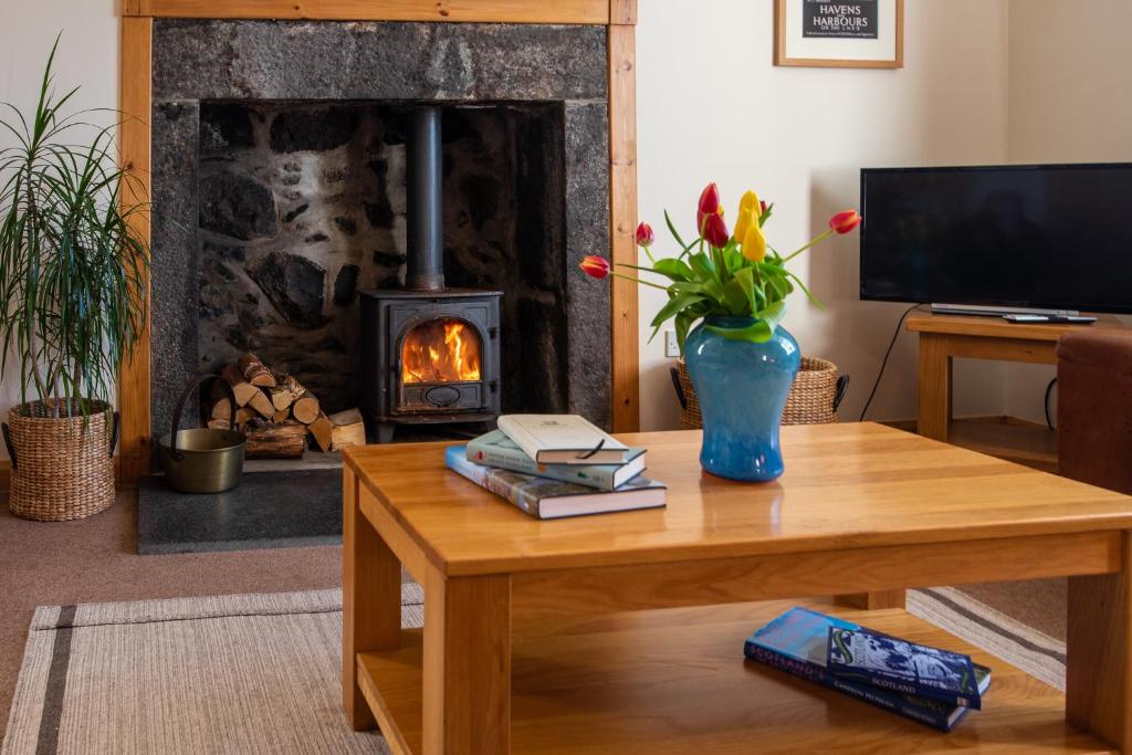 uma sala de estar com uma mesa e uma lareira em Hillside Cottage em Aberdeen