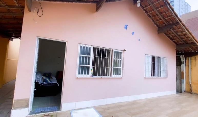Seu Cantinho na Vila Tupi 3 Dormitórios في برايا جراندي: منزل وردي مع نافذتين وغرفة معيشة