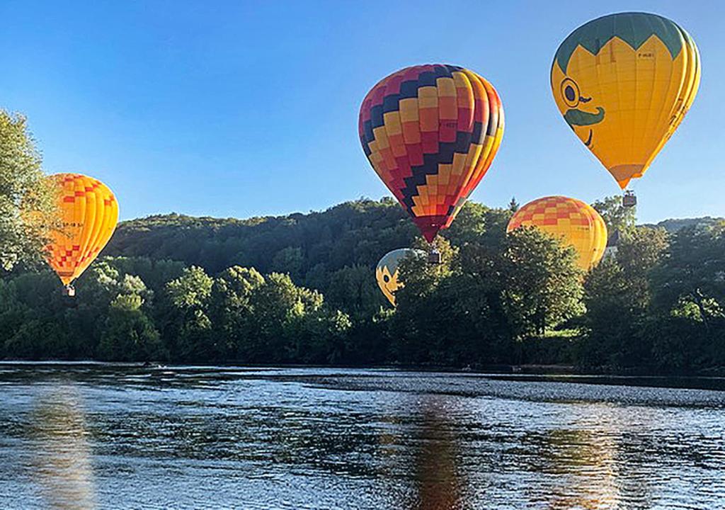 a group of hot air balloons flying over a river at Au coeur de Beynac, une maison de caractère avec jardin terrasse in Beynac-et-Cazenac