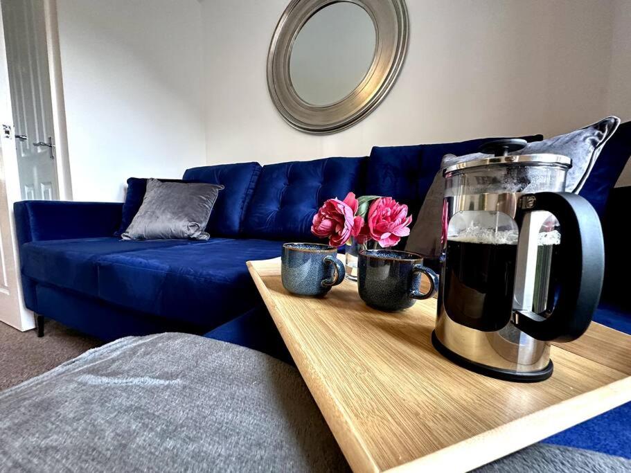 a living room with a blue couch and a table with flowers at Dale House by Blue Skies Stays in Middlesbrough