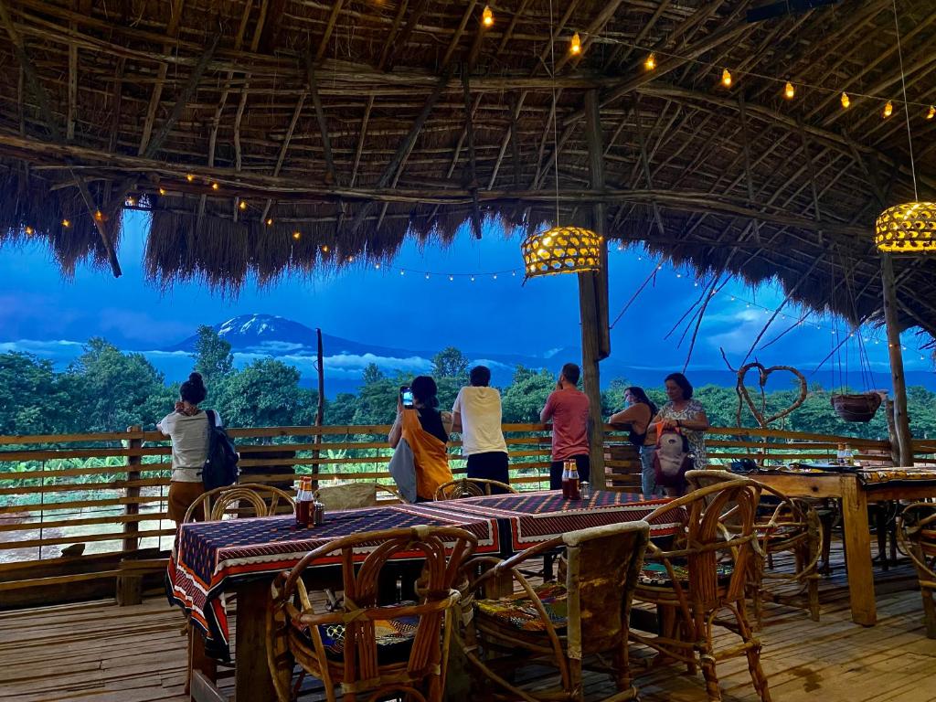 a group of people standing around a table in a restaurant at Mount Kilimanjaro 360 view Cottage in Uru