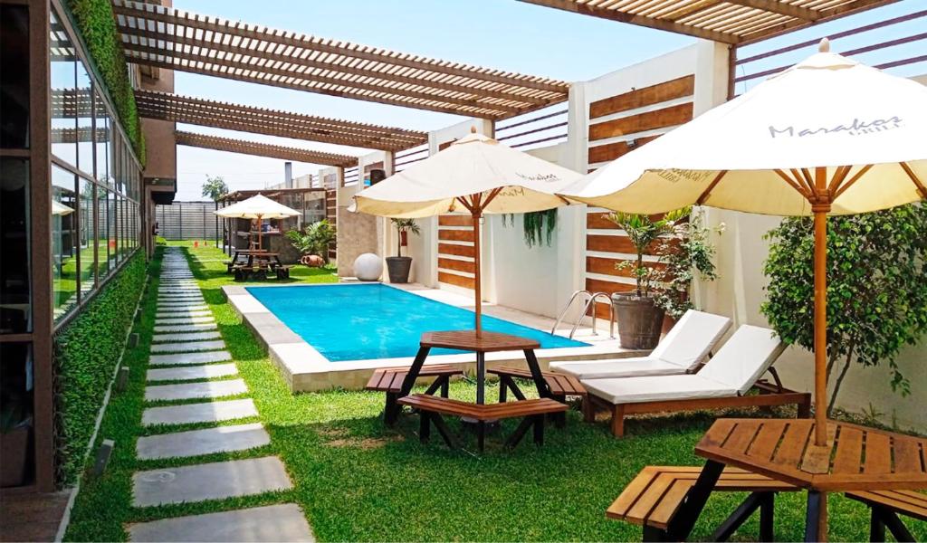 un cortile con piscina e due tavoli e ombrelloni di Marakos Pimentel a Pimentel