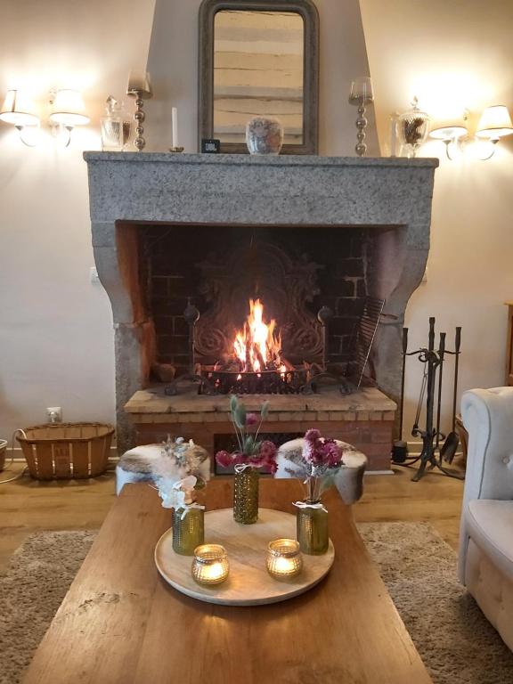 a fireplace in a living room with a table in front of it at Les Bessonnes in Saint-Georges-Haute-Ville