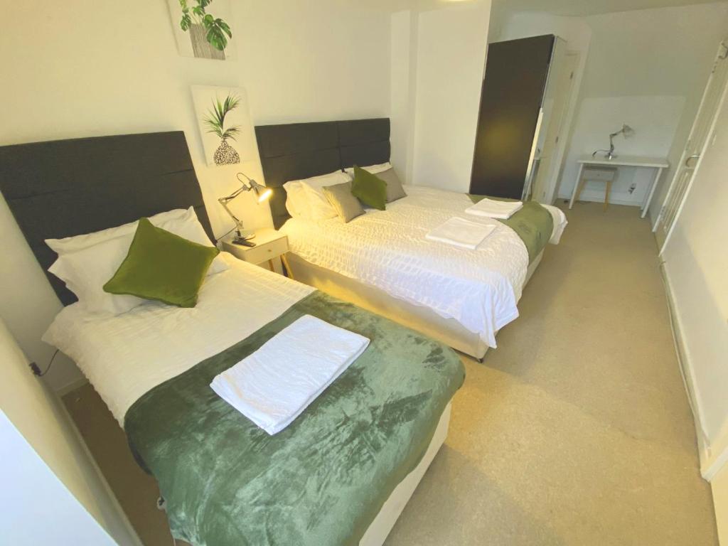 1 dormitorio con 2 camas con sábanas verdes y blancas en The Woodcutter - Competitive rates Walsall, en Walsall