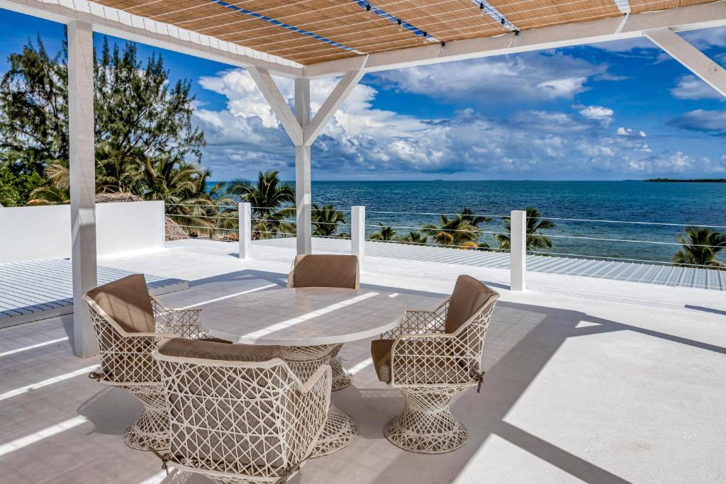 um pátio com uma mesa e cadeiras e o oceano em White Sands Beach House em Maya Beach