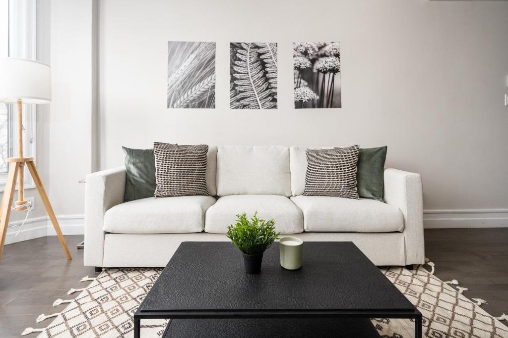 Plateau Prime Residence في مونتريال: غرفة معيشة مع أريكة بيضاء وطاولة قهوة