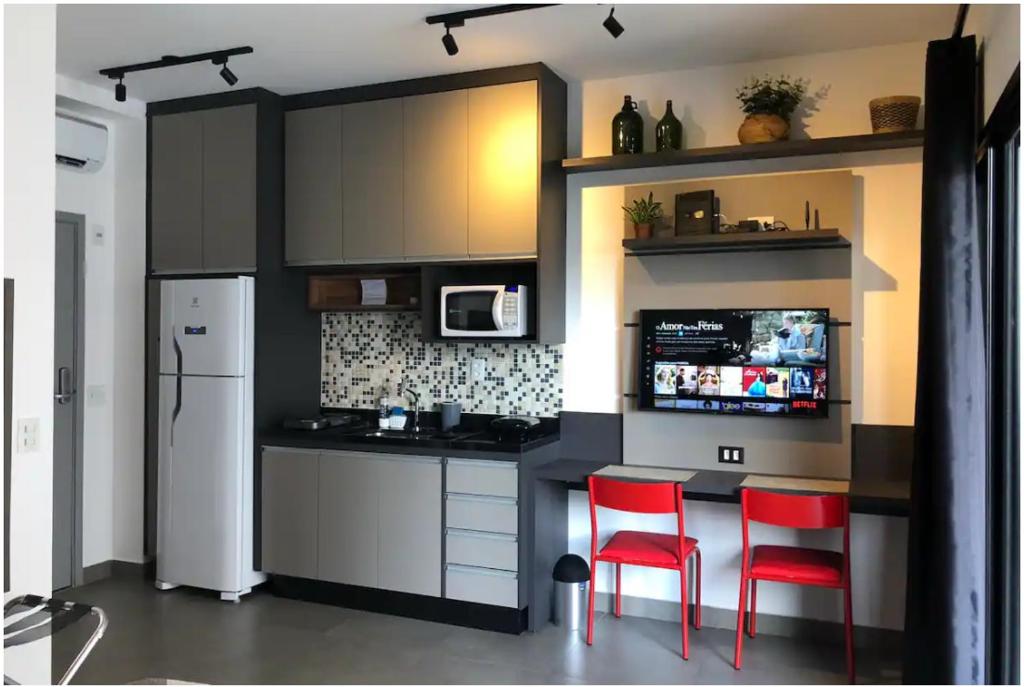 eine Küche mit zwei roten Stühlen und einem Kühlschrank in der Unterkunft Studio novo ao lado da Oscar Freire in São Paulo