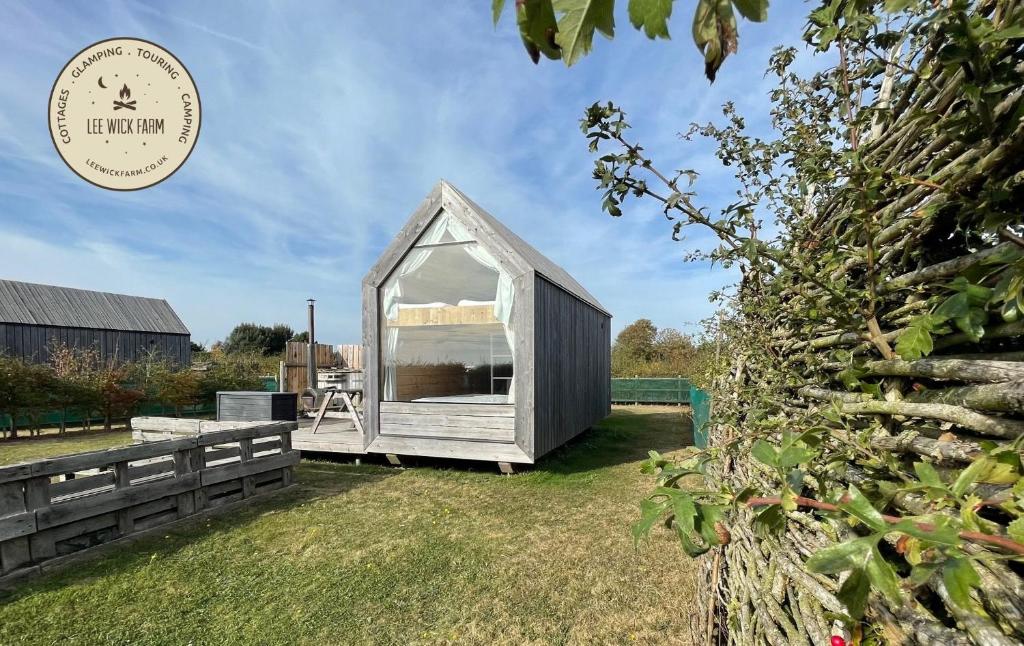 a small grey greenhouse in a yard with grass at Lushna 6 Petite at Lee Wick Farm Cottages & Glamping in Clacton-on-Sea