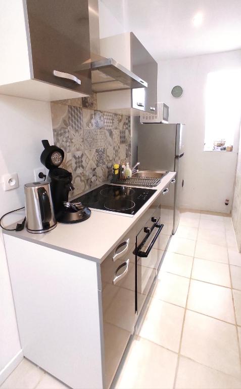 a white kitchen with a sink and a stove at Logement entier proche des châteaux - 1 à 6 Pers - in Barsac