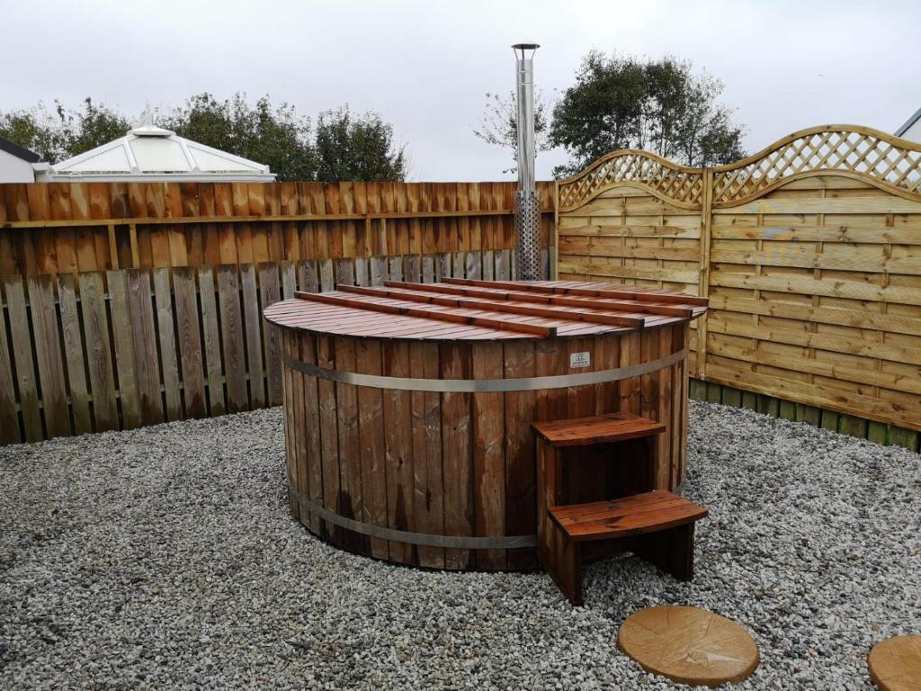 a hot tub in a backyard with a wooden fence at Cornish Coastal Bungalow in Padstow