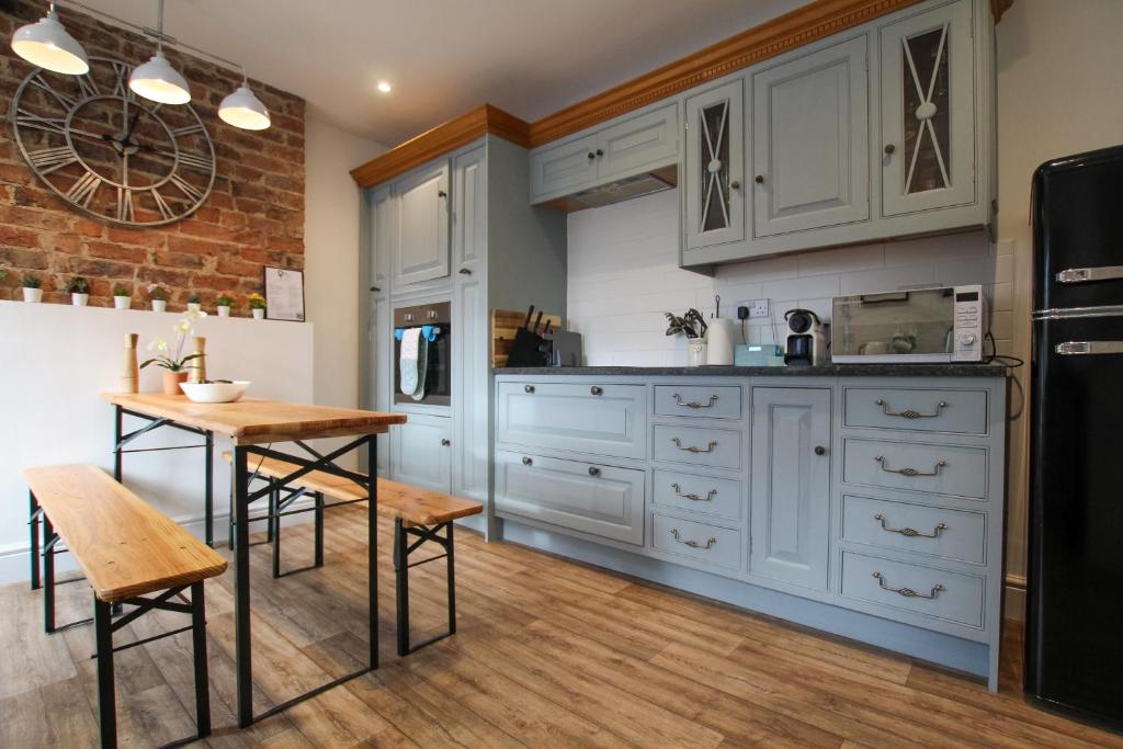 uma cozinha com armários brancos e uma mesa de madeira em Fairways View - Spacious Apartment - Sleeps 6 - Lovely Views em Hoylake