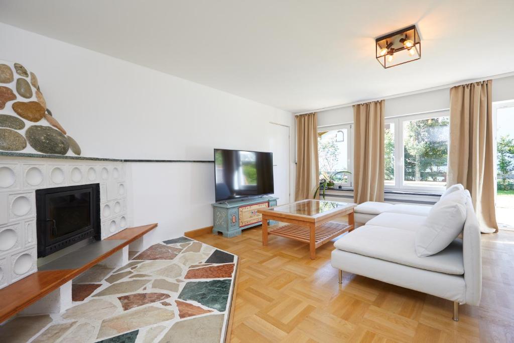 a living room with a white couch and a fireplace at Ferienwohnung zum Hirschgarten in Krün