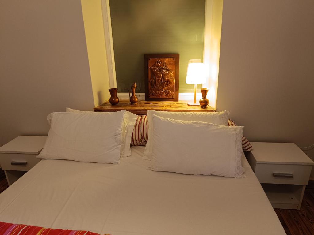 een slaapkamer met een wit bed met witte kussens bij flora's memories appartment in Kavala