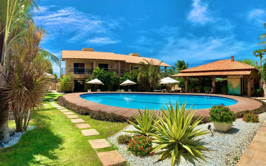 a resort with a swimming pool and a house at Pousada Refúgio Jardim de Canoa by Borboleta in Canoa Quebrada