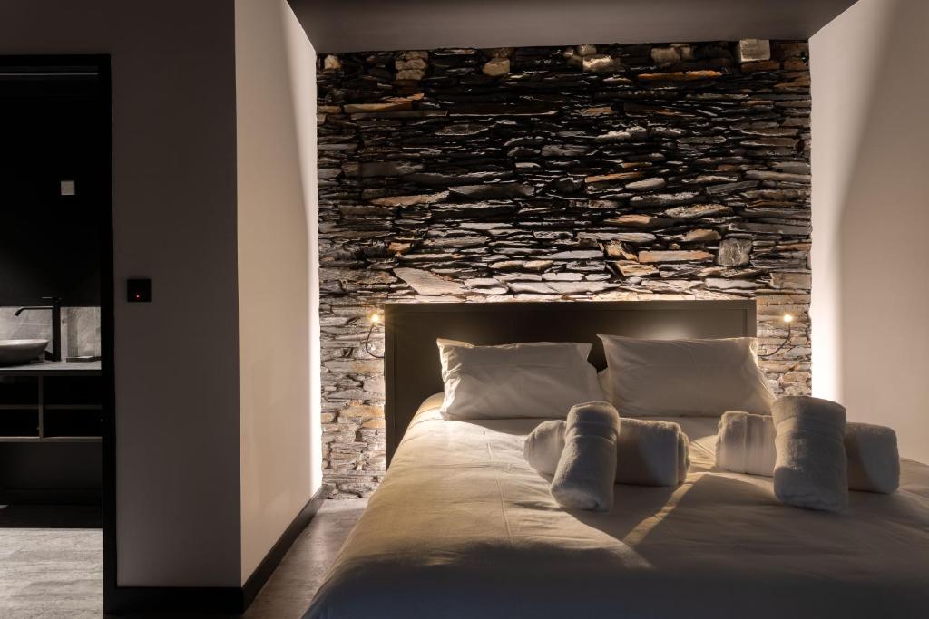 a bed in a room with a stone wall at L'Ardoise, L'Anjou, La Vigne et La Loire in Angers
