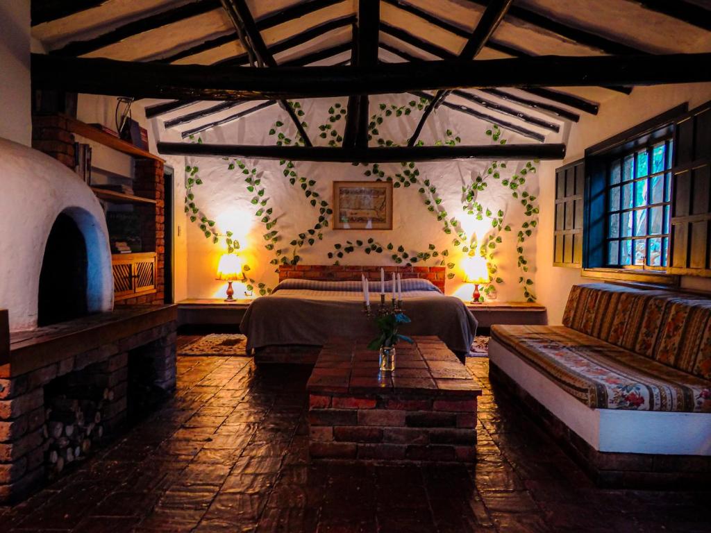 um quarto com uma cama e um sofá num quarto em Hotel Hacienda Suescún em Tibasosa