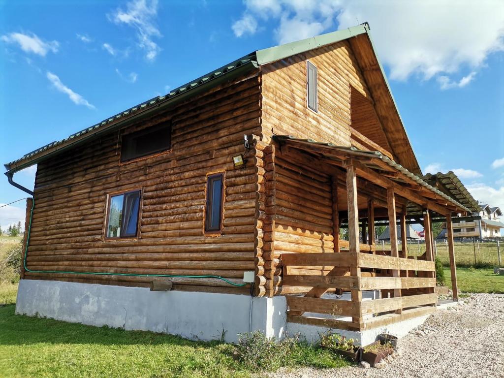 a log cabin with a porch on the side of it at Căsuța de munte in Mărişel