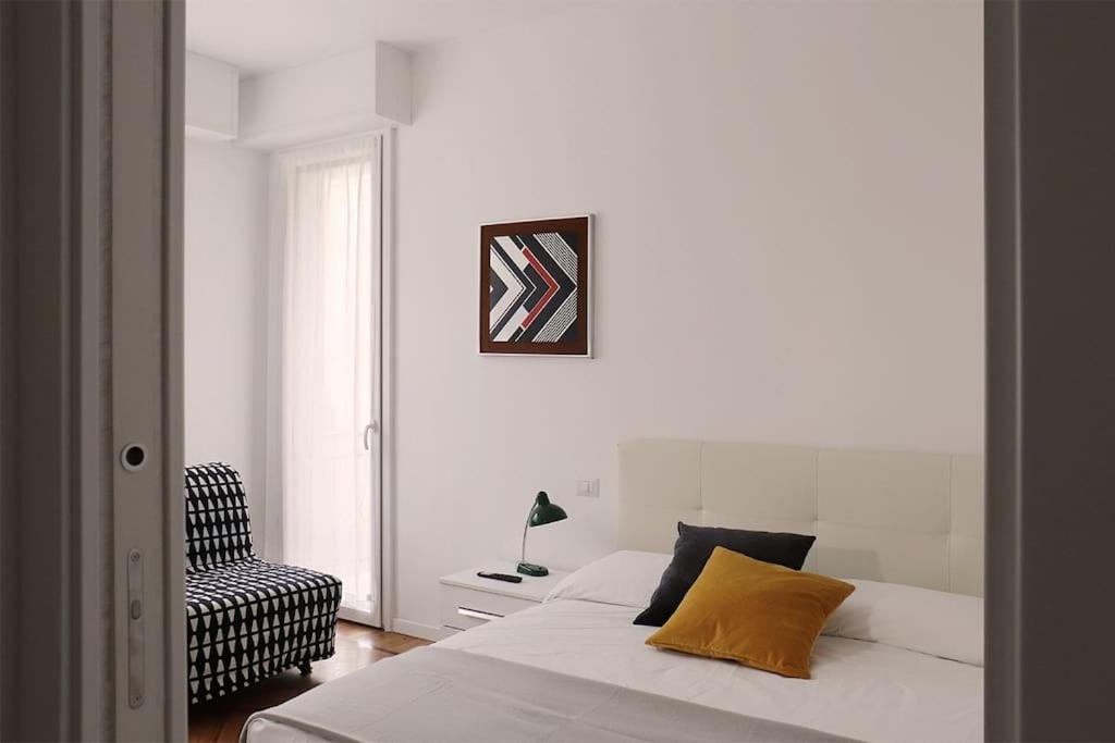 1 dormitorio blanco con 1 cama y 1 silla en Appartamento Lorenteggio - Piazza Frattini affaccio interno, 2 balconi, en Milán