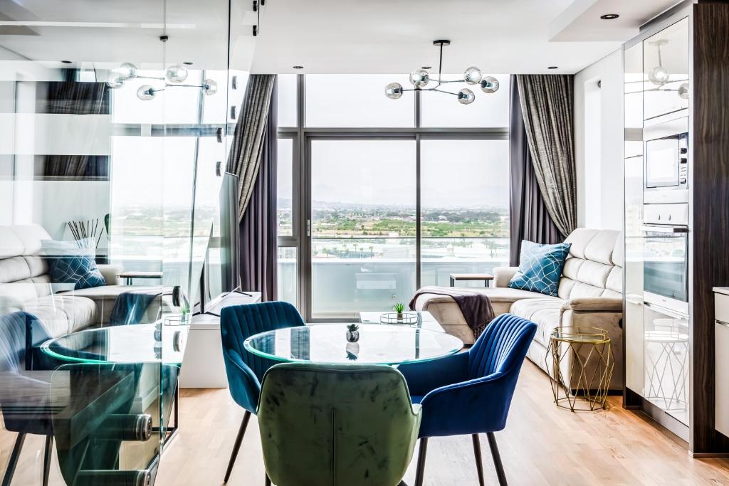 sala de estar con mesa de cristal y sillas azules en Belina - Crystal Towers Presidential Penthouse, en Ciudad del Cabo