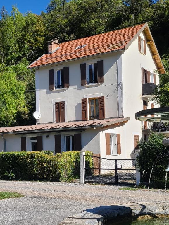 une maison blanche avec des fenêtres marron et une clôture dans l'établissement Le Gite de Maminou classé 3 étoiles, à Saint-Julien-en-Beauchêne