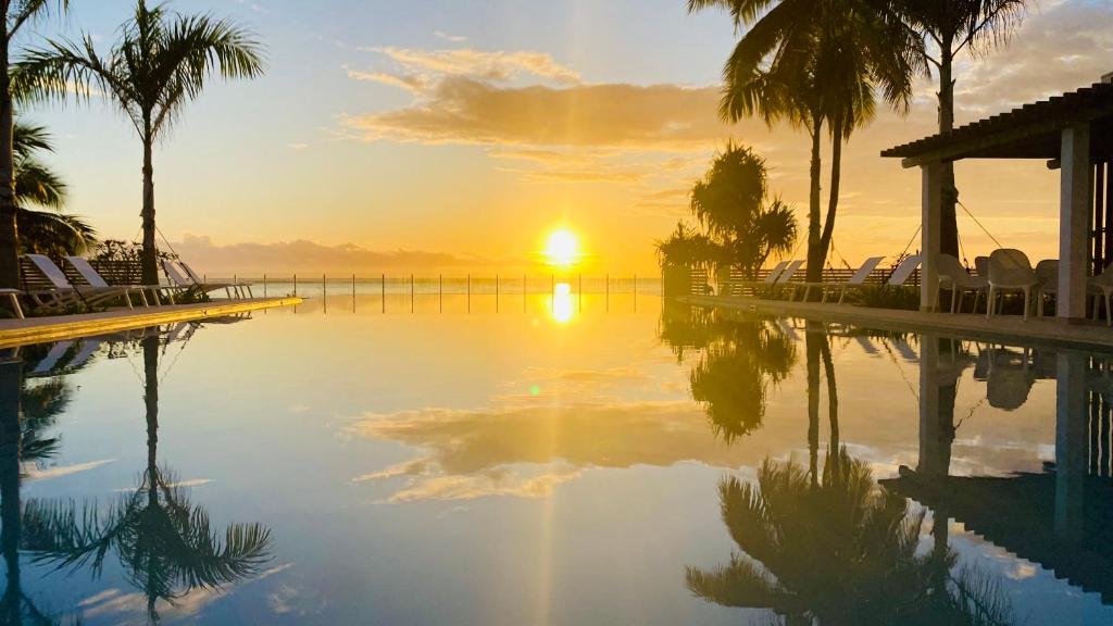 puesta de sol sobre una piscina con palmeras en Villa TE URA Beach, en Paea