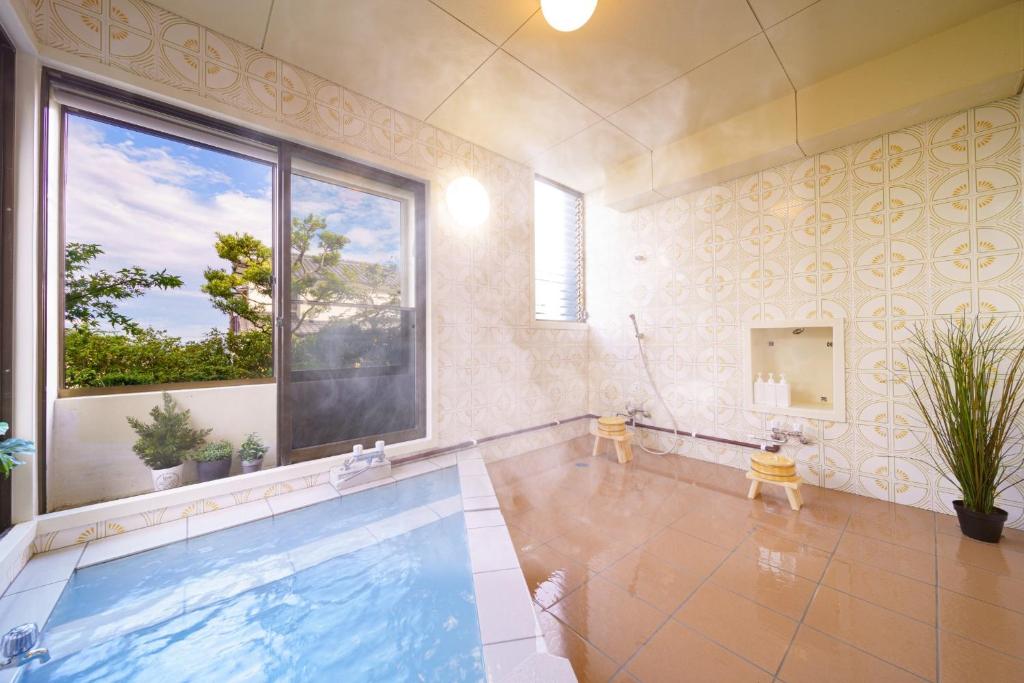 a swimming pool in a room with a large window at Kiseki no Aoi Tennenonsen - Vacation STAY 15697 in Beppu