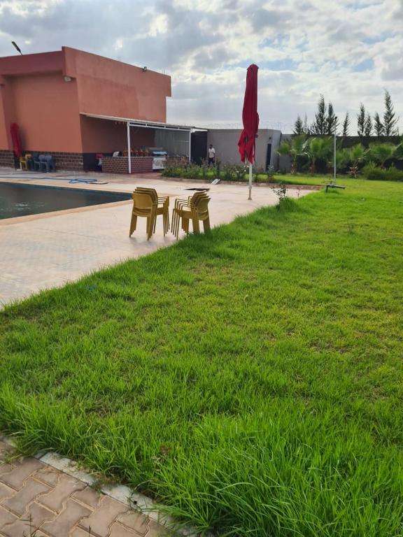 Deux chaises et une table dans l'herbe près d'un bâtiment dans l'établissement Maison d’hôtes SOUIHLA, à Oulad Sidi Cheïkh