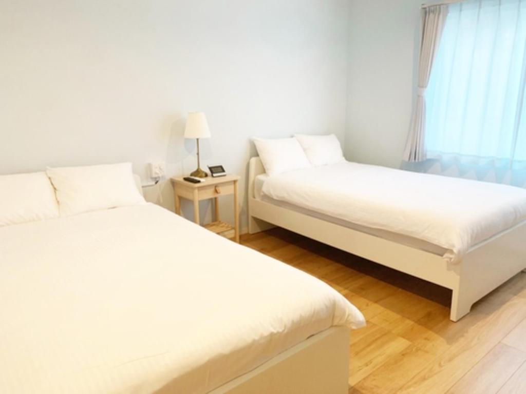 HOTEL SANDRIVER ISHIGAKIJIMA - Vacation STAY 91454v في جزيرة إيشيغاكي: غرفة نوم بسريرين ونافذة