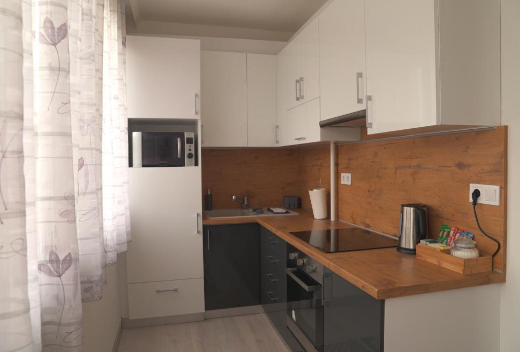 a kitchen with white cabinets and a wooden counter top at Zoé Apartman Debrecen Nagyerdő in Debrecen