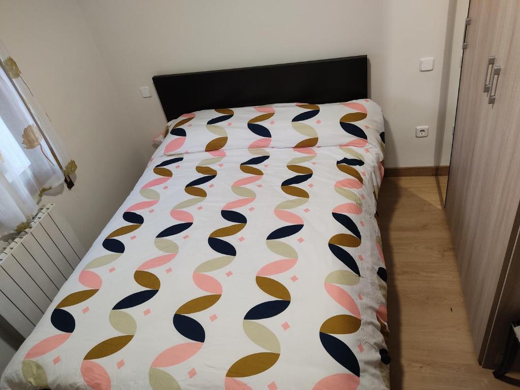 una camera da letto con un letto con un piumone colorato di Apartamento Abrantes a Madrid