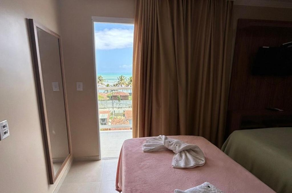 a hotel room with a bed and a window with a view at FLAT BADEJO in Japaratinga