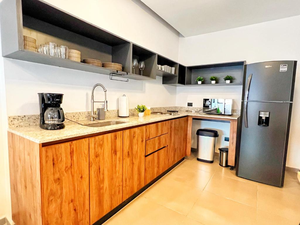 a kitchen with wooden cabinets and a refrigerator at Bosqüa SmartAppt34 II Pool II 4MindePaseoMontejo II Wifi60Gb in Mérida