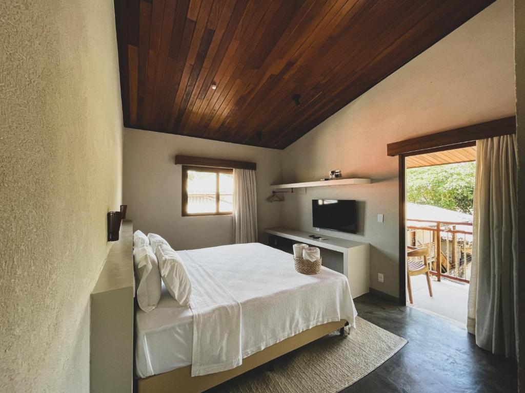 1 dormitorio con 1 cama con techo de madera en AL MAR SUÍTES, en Praia do Forte