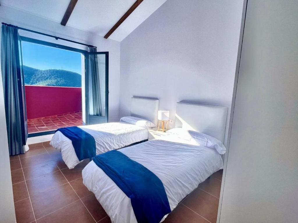 2 Betten in einem Zimmer mit einem großen Fenster in der Unterkunft Corazón de Javalambre 